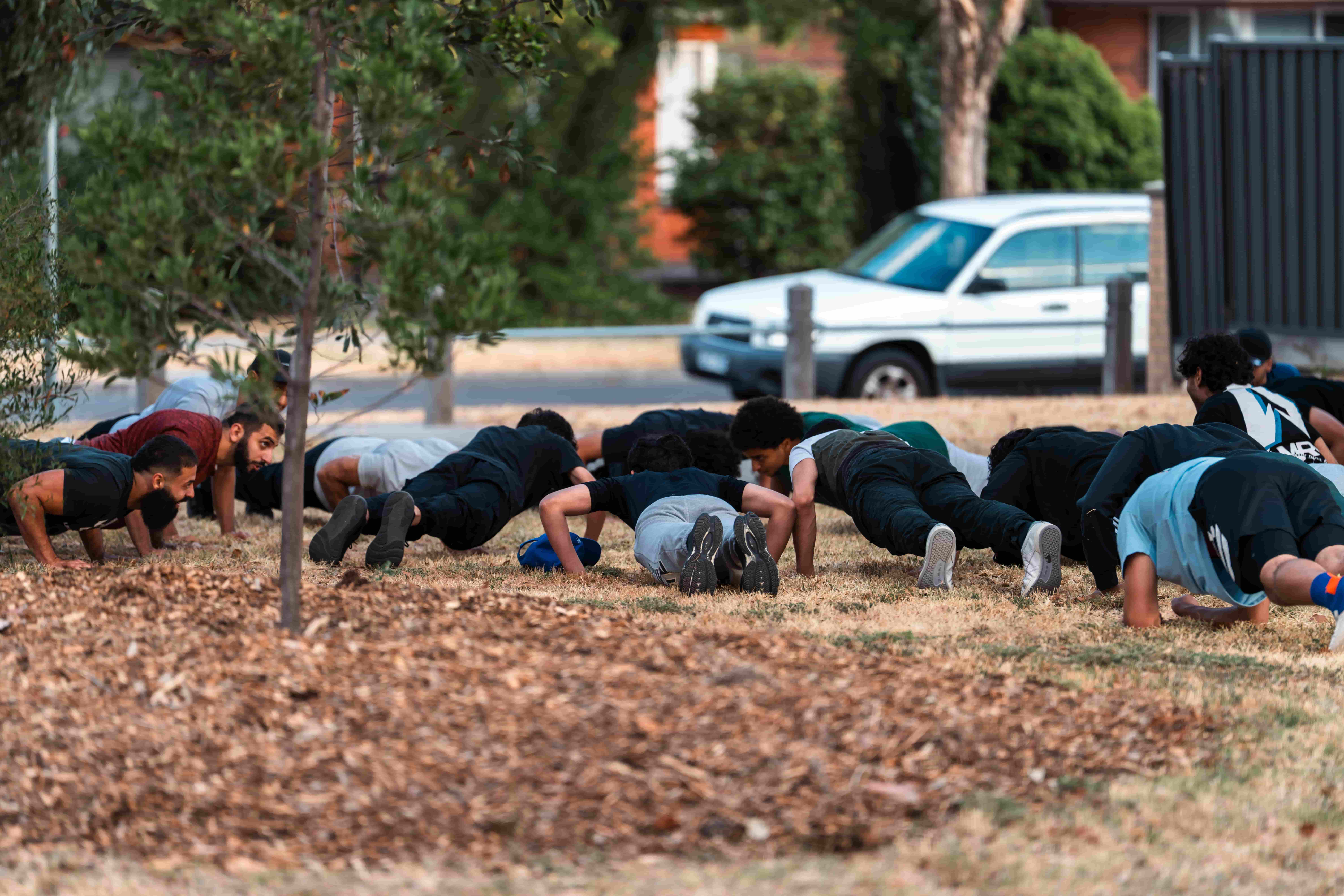 A group doing push-ups on the grass at an outdoor UMF training session