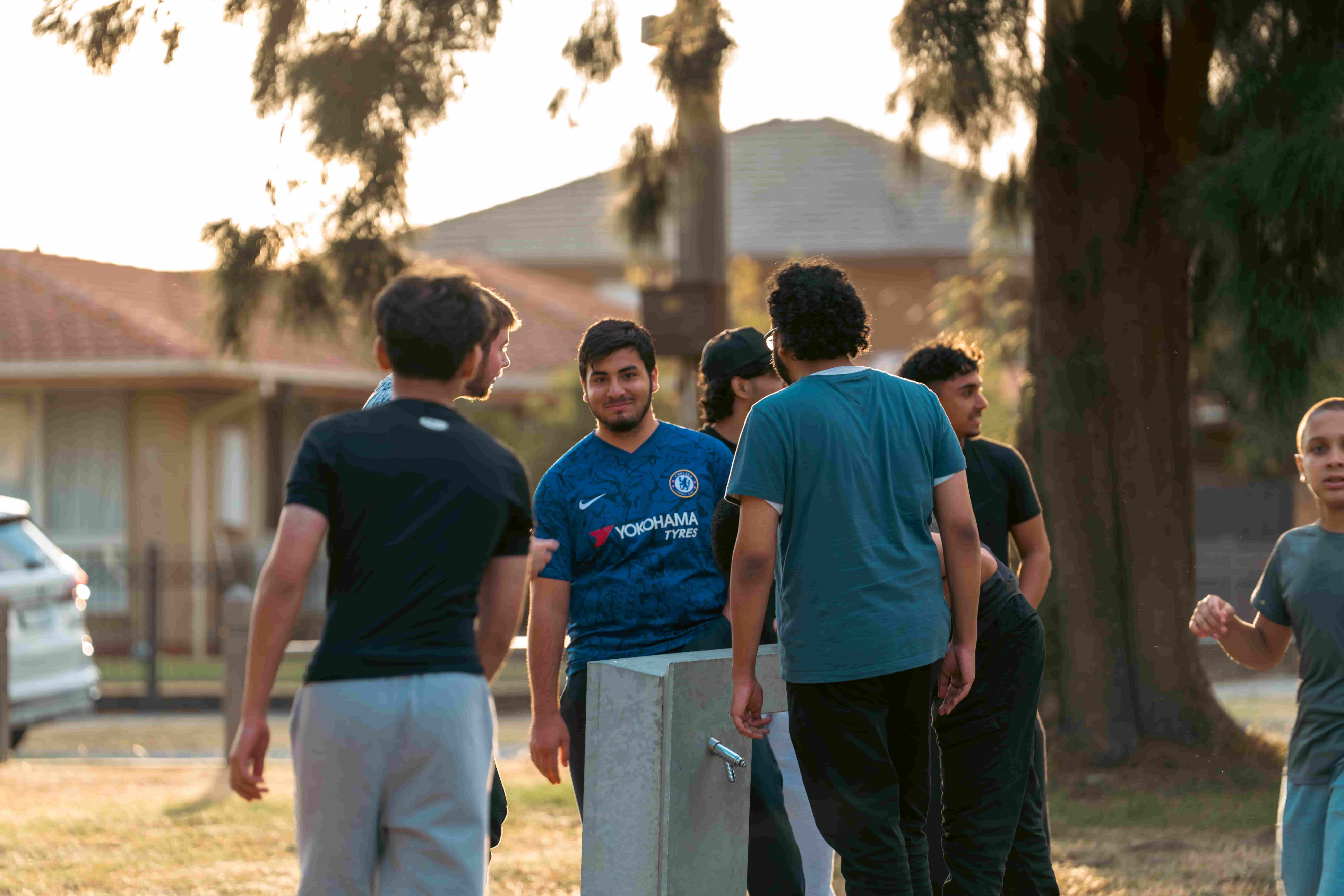 Young people talking together in a park at golden hour after training